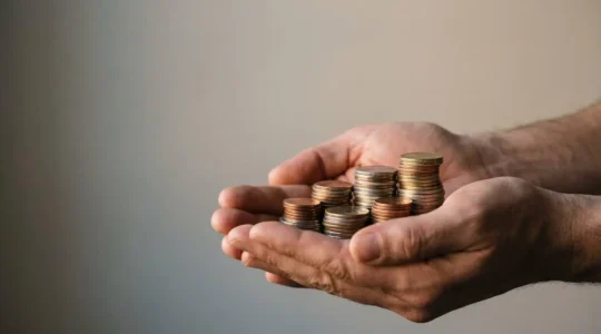 Hands protecting stacked coins symbolizing emergency fund growth against inflation with soft natural lighting